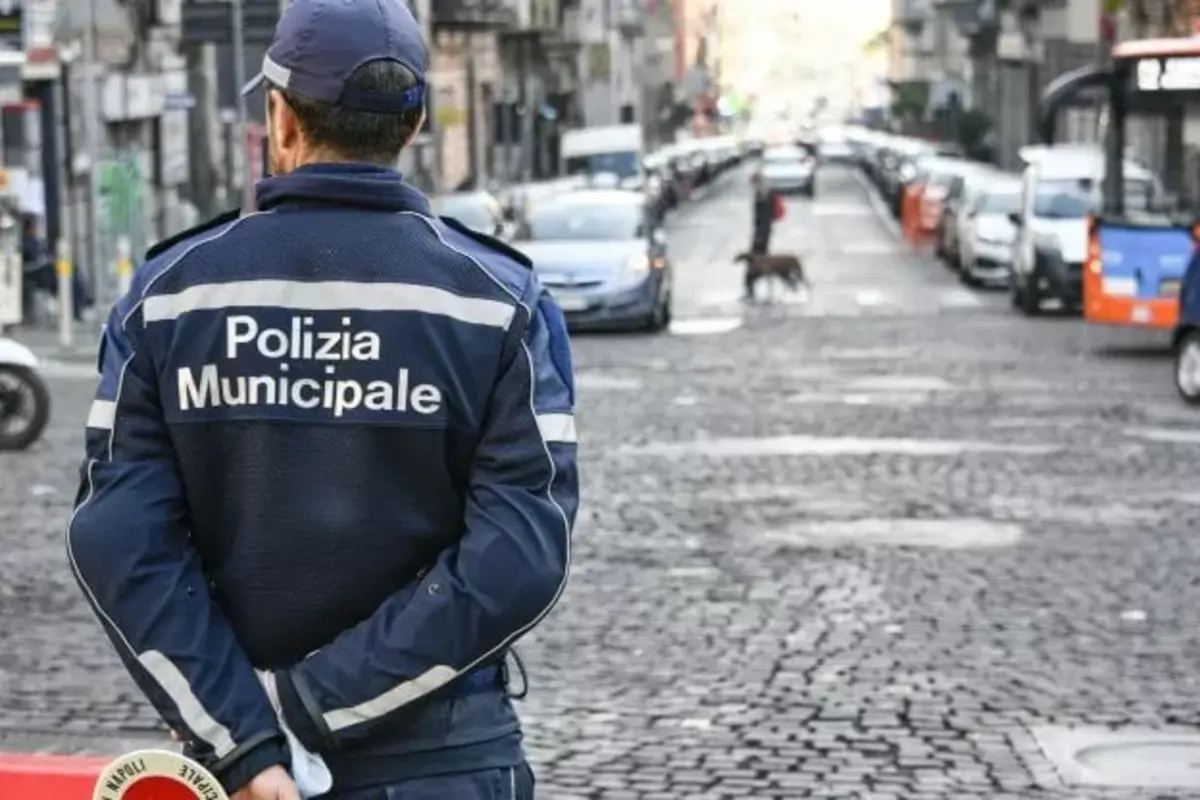 Operatore di Polizia Locale lungo una strada con veicoli in sosta