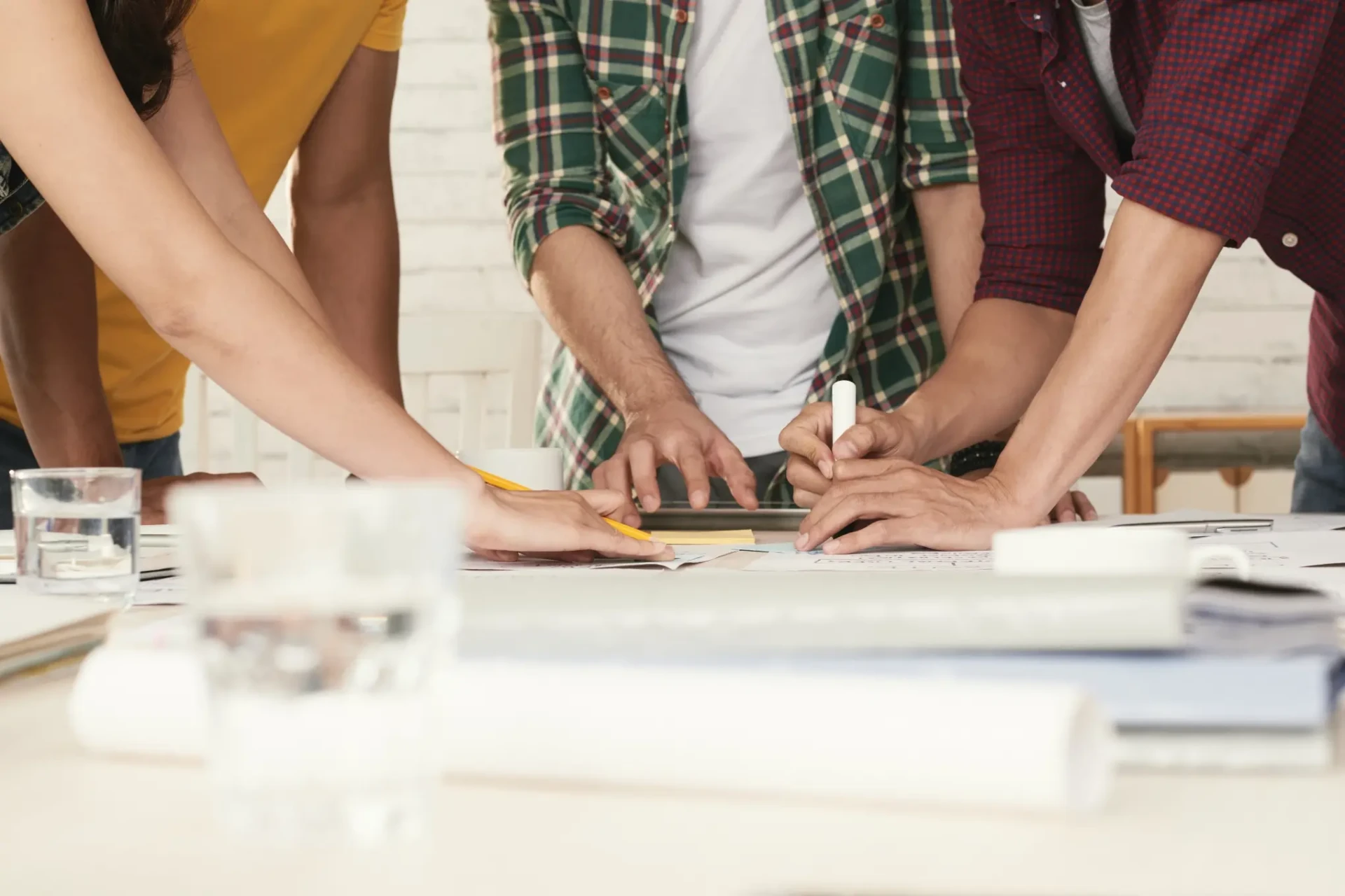Mani di più persone al lavoro su documenti condivisi attorno a un tavolo